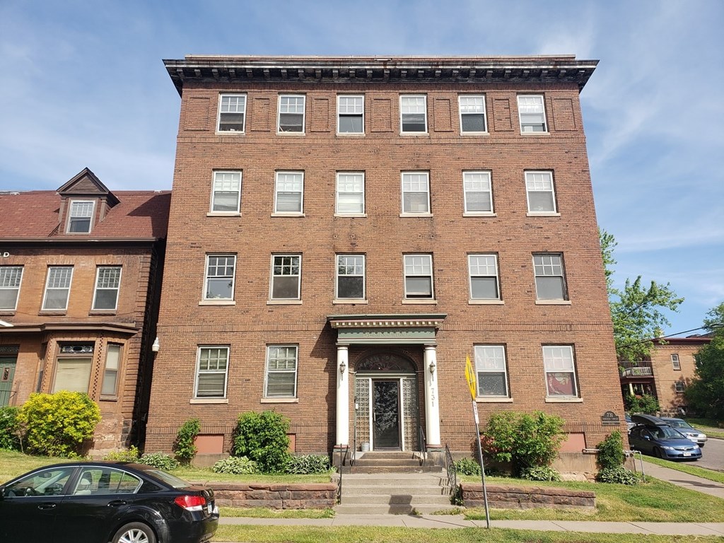 A black car is parked in front of a red brick building.