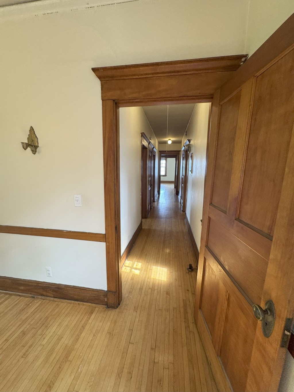 A hallway with a wooden floor and a wooden door.