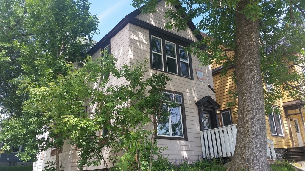 A house with a white fence and a tree in front of it.