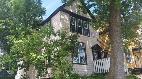 A house with a white fence and a tree in front of it.