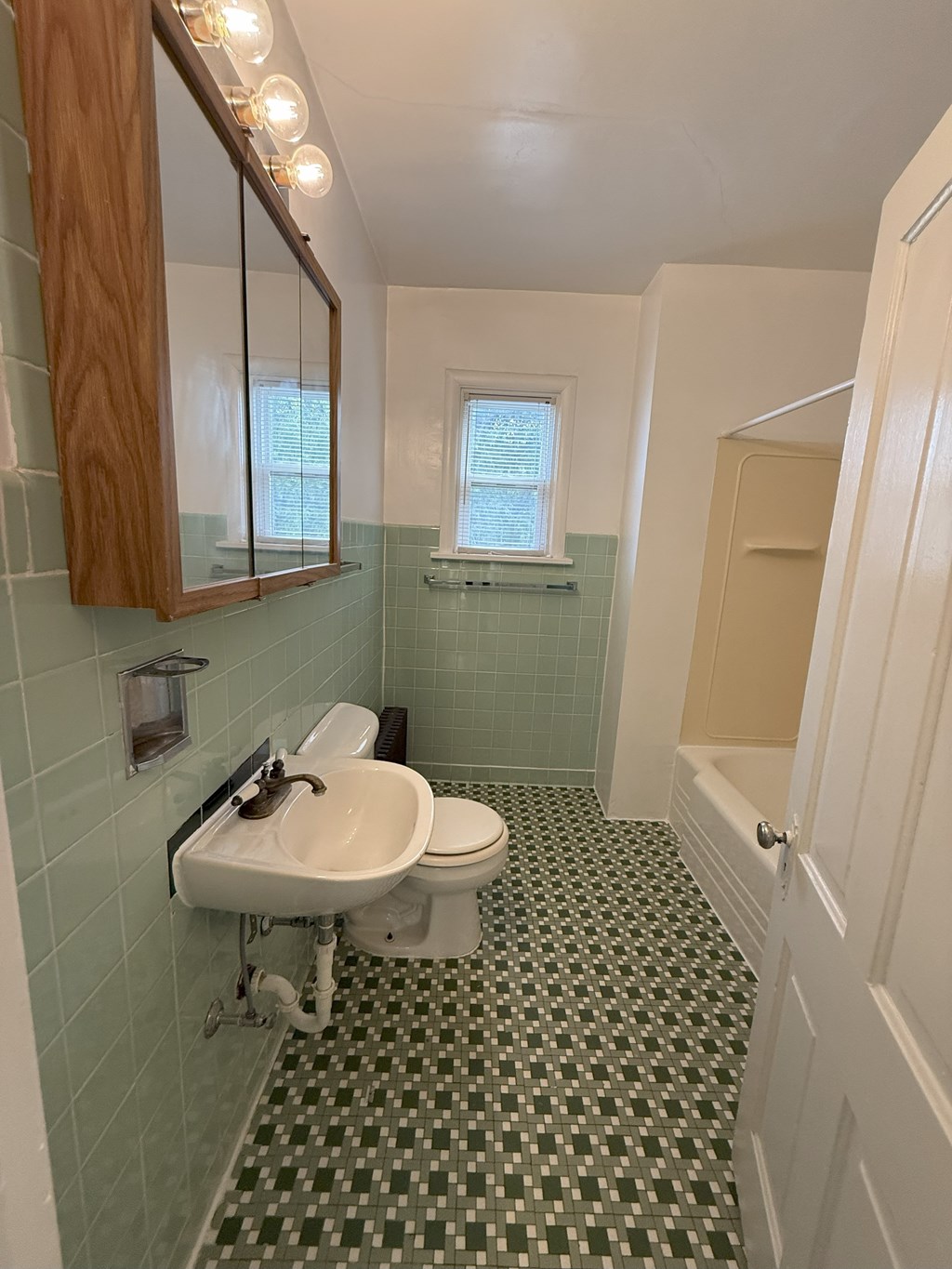 A bathroom with a green tiled floor and a white sink.