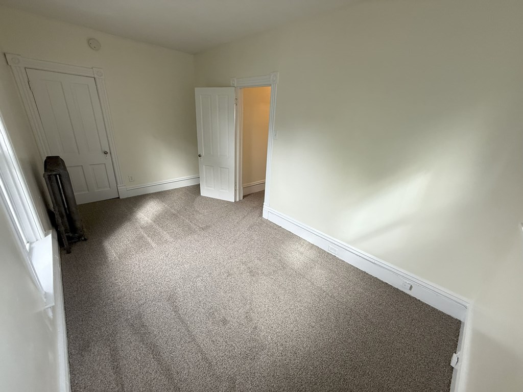 A room with a carpeted floor and a vacuum cleaner.