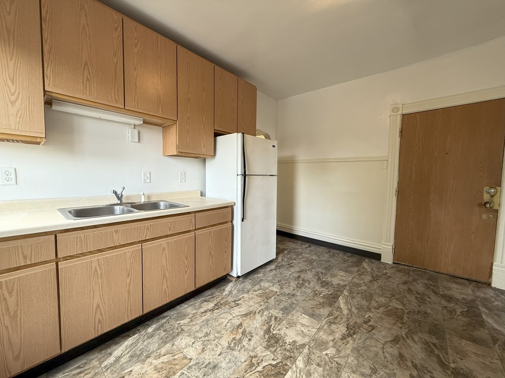 A kitchen with wooden cabinets and a white refrigerator.
