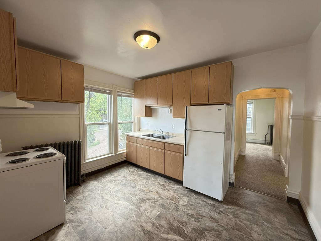 A kitchen with a white refrigerator and wooden cabinets.