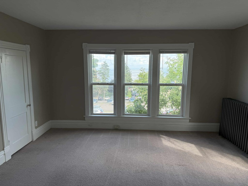 A room with a carpeted floor and a large window.