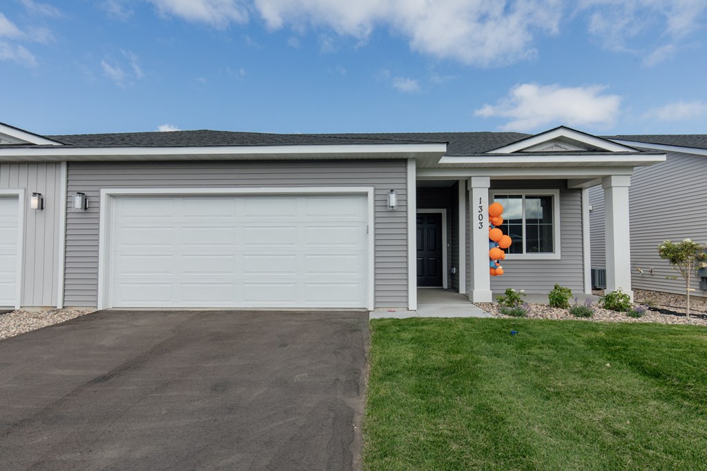 a gray house with a white garage door and a lawn