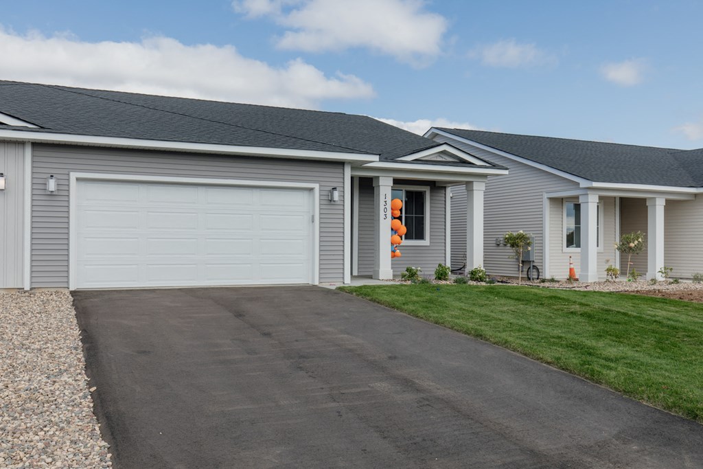 a gray house with a white garage door and a driveway