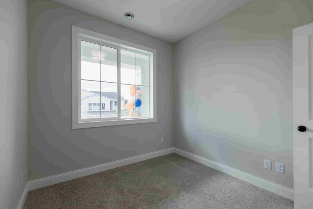 a bedroom with a window and a carpet