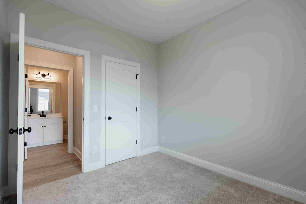 a bedroom with white walls and a door to a bathroom