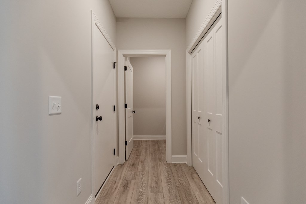 an empty hallway with white doors and white walls and wood floors