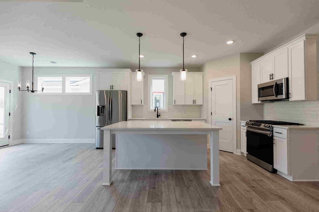 an open kitchen with white cabinets and a large island