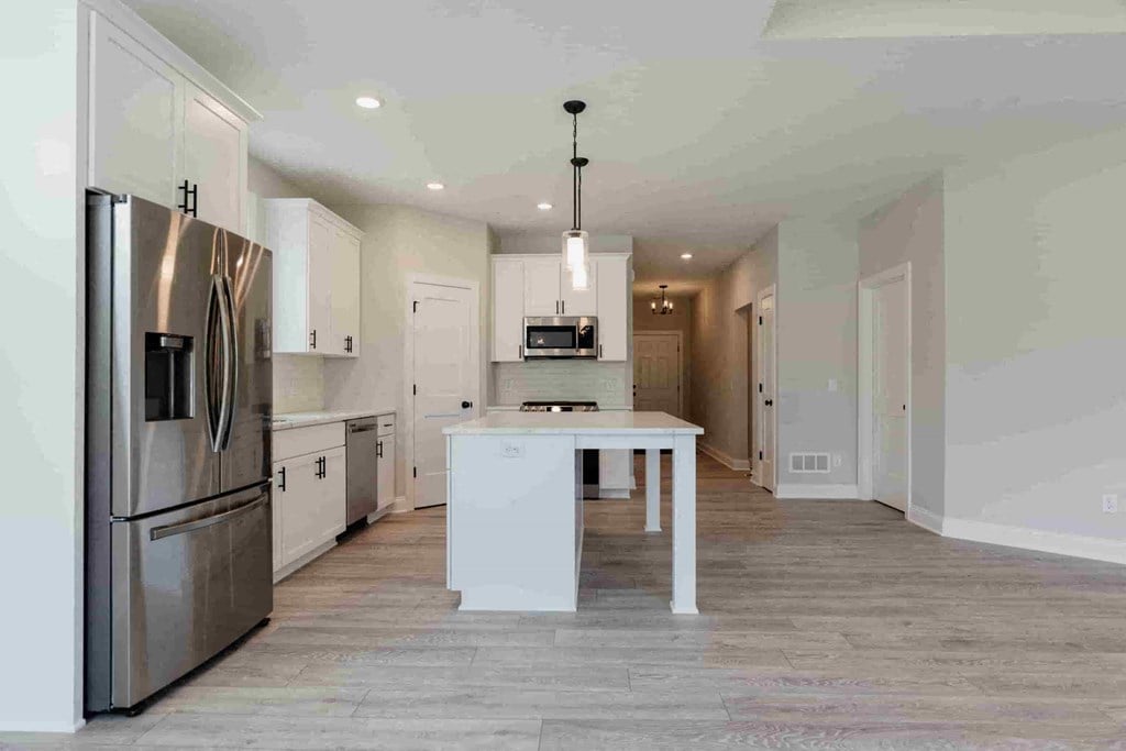 a large white kitchen with stainless steel appliances and a white island