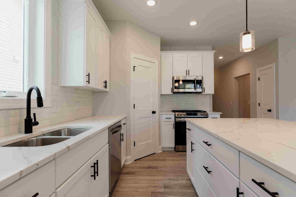 a kitchen with white cabinets and white counter tops and a sink