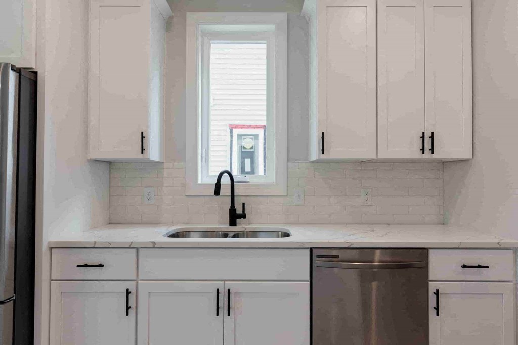 a kitchen with white cabinets and a window above the sink
