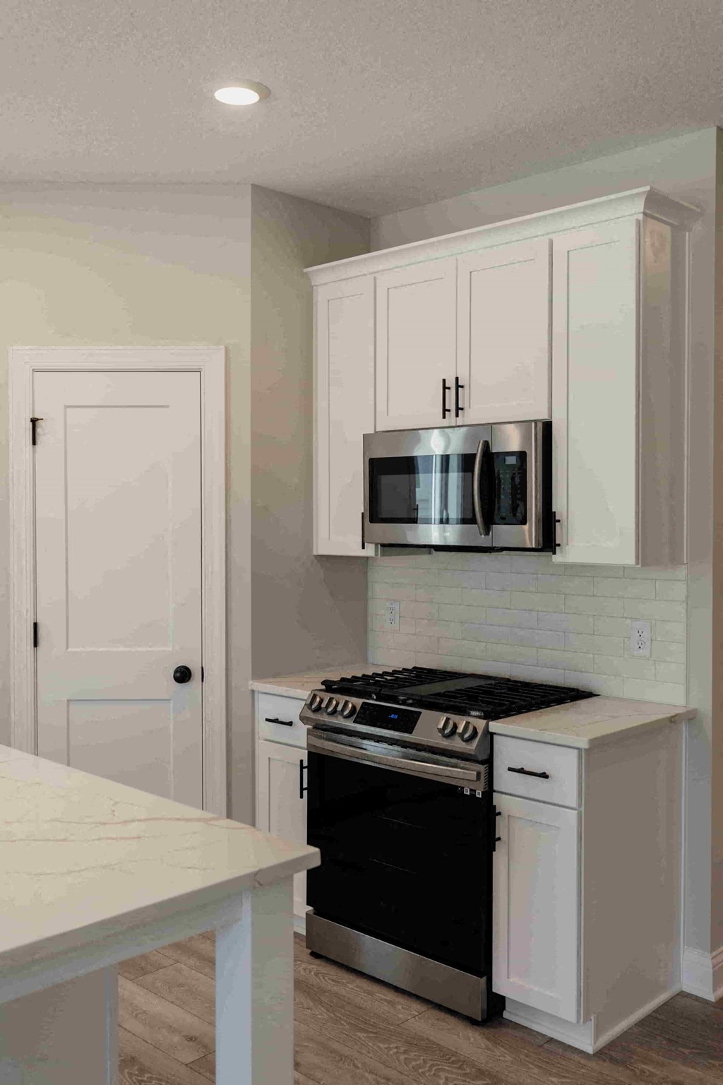a kitchen with white cabinets and a stove and a microwave