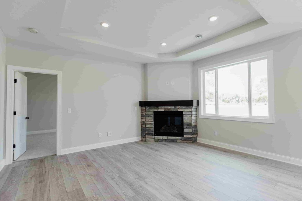 an empty living room with a fireplace and wooden floors