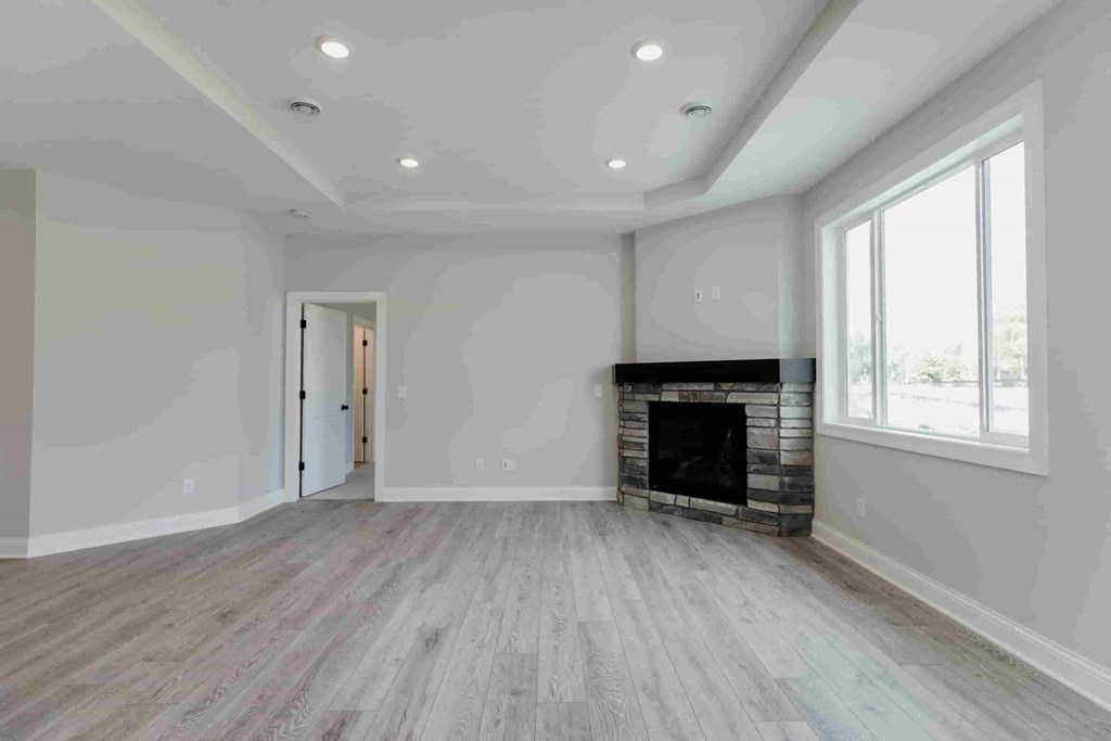 an empty living room with a fireplace and wooden floors