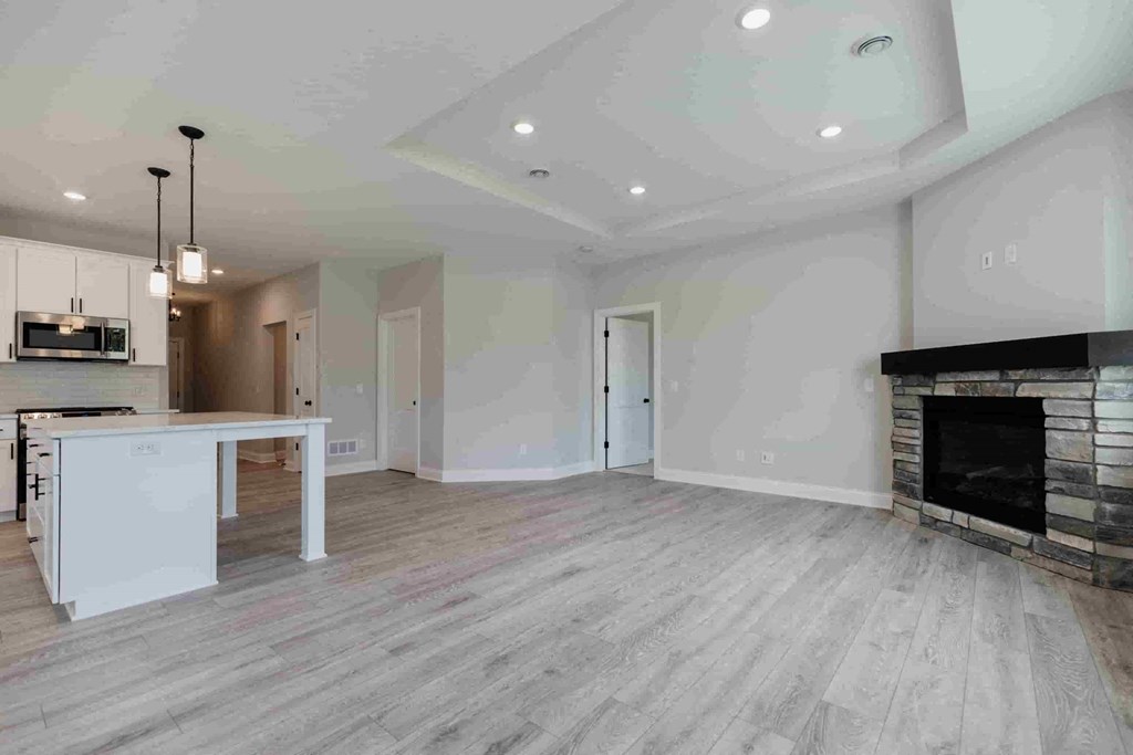 an empty living room with a fireplace and a kitchen