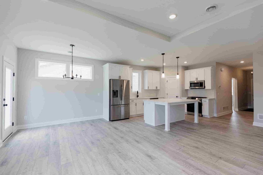 an empty kitchen with white walls and wood floors