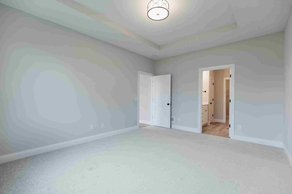 an empty living room with white walls and a door to a hallway