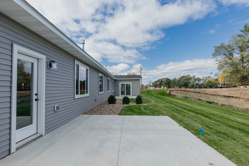 the front of a gray house with a concrete driveway and a grass field
