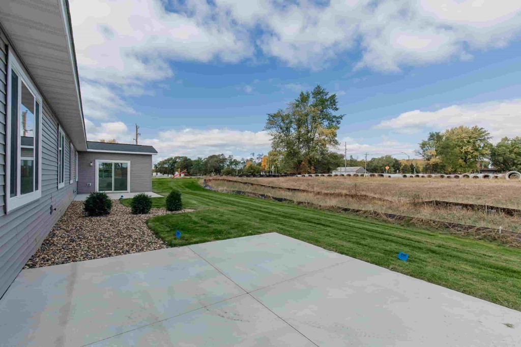 a view of the side of a house with a driveway and a grassy yard
