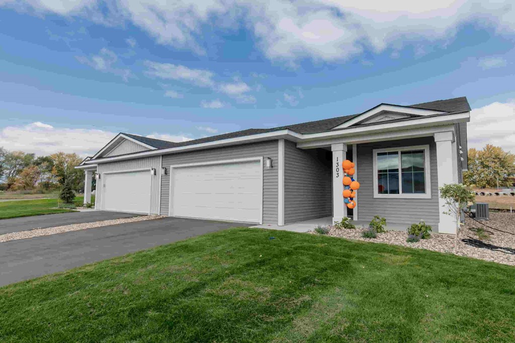 a gray house with a driveway and a lawn