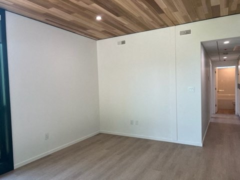 A room with a wooden ceiling and light brown flooring.