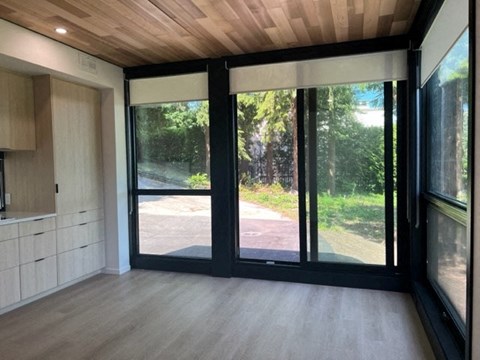 A modern interior with a view of a tree-lined road through the glass doors.