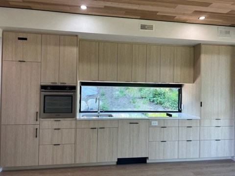 A kitchen with wooden cabinets and a television mounted above the counter.