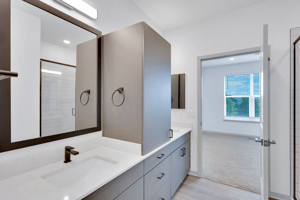 Master bath with two sinks, vanity and glass door shower.