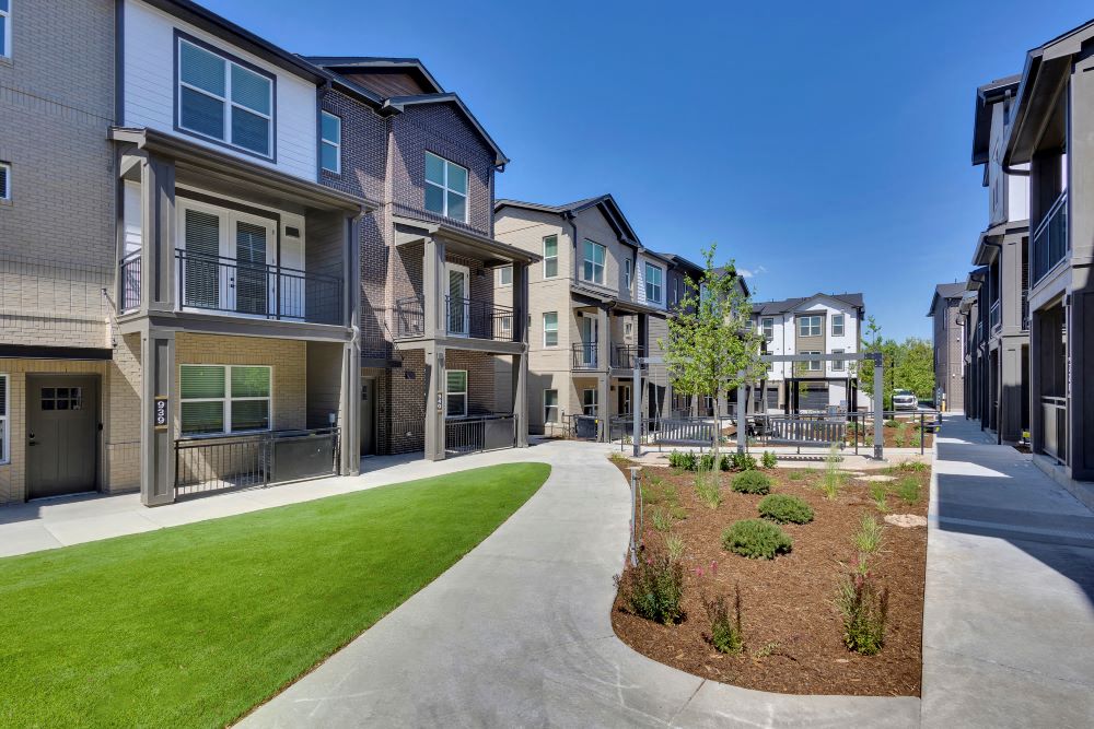 View from outdoor courtyard with walkway, grass and townhomes in background