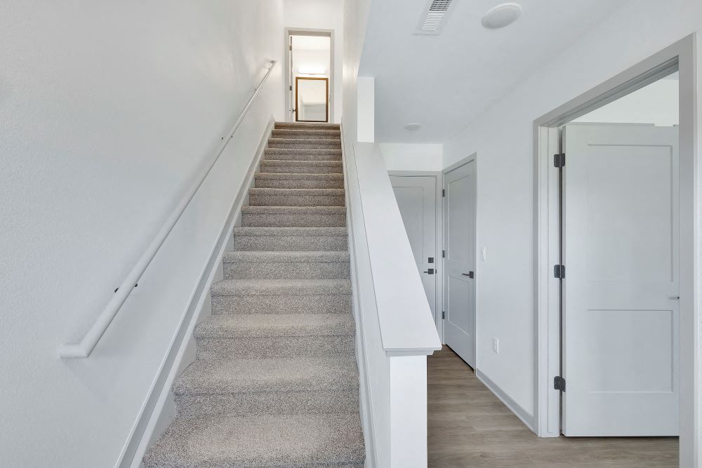 View from the front door with stair case on the left and a bedroom and garage entrance to the right.