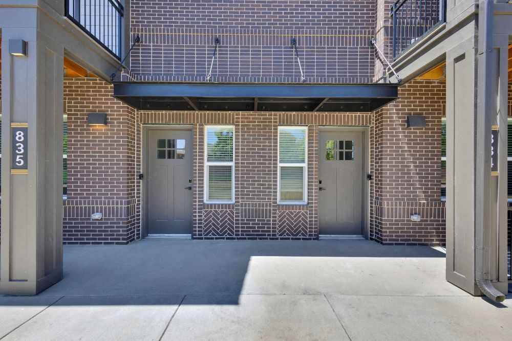 View of two townhome doors with brick background and second floor balconies