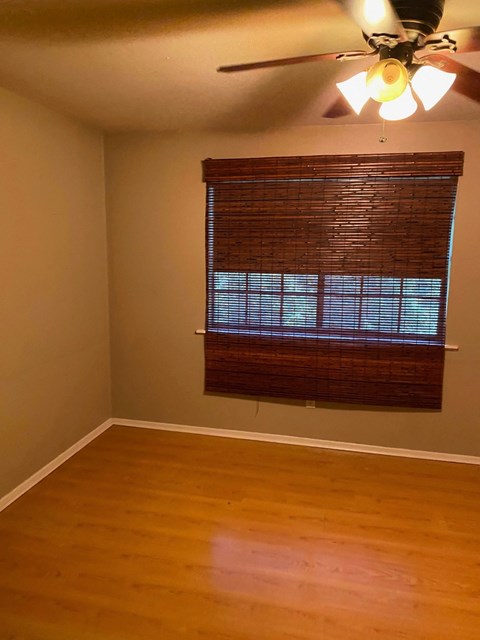 an empty living room with a window and a ceiling fan