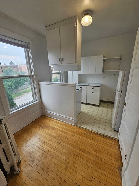 A kitchen with white cabinets and a wooden floor.