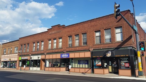 A street view of a brick building with various storefronts.