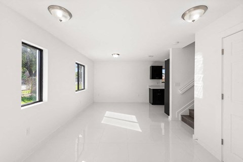 an empty living room with white walls and white tile floors
