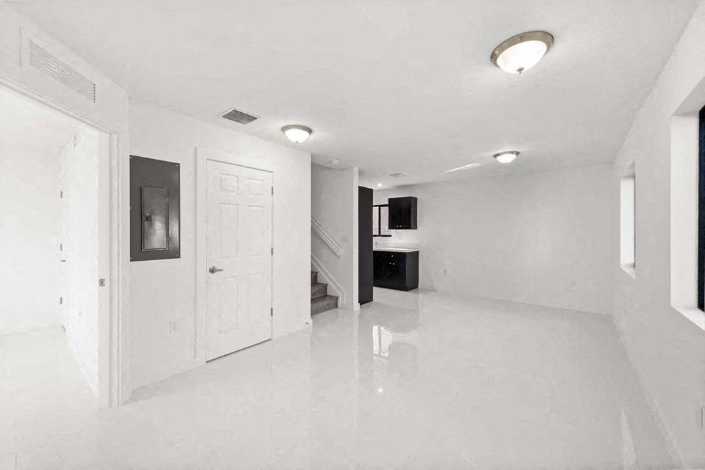 an empty white room with a white door and a staircase