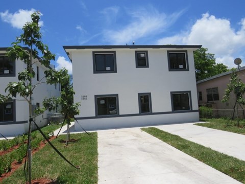 the back of a white building with a sidewalk and grass