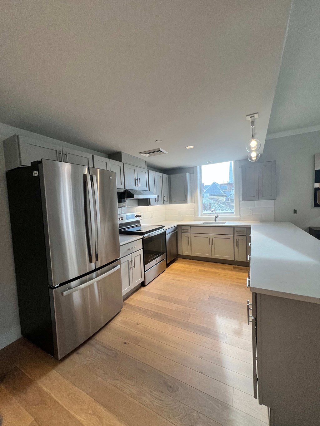 a renovated kitchen with stainless steel appliances and white cabinets