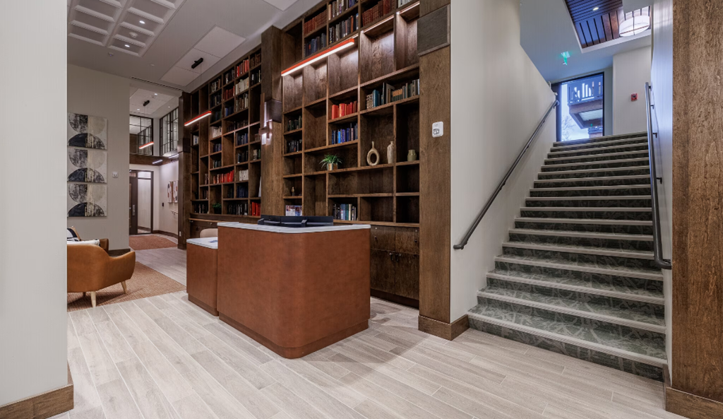the lobby of a building with a staircase and bookshelves