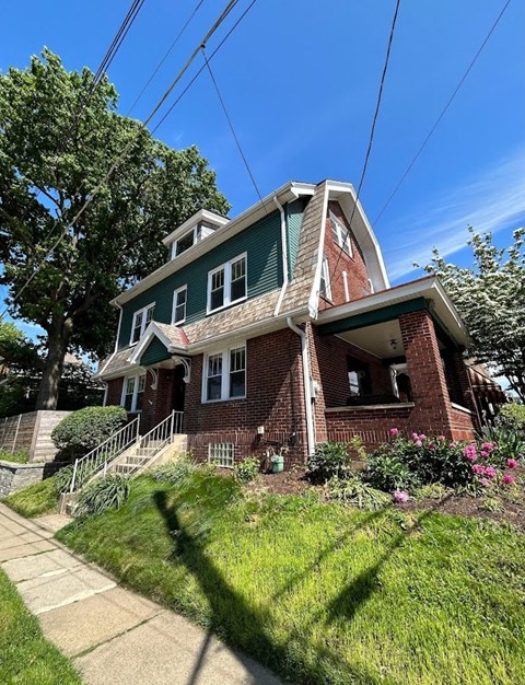 A red brick house with green trim and a white window.