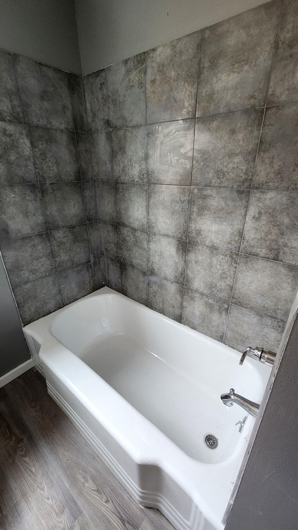 a white bath tub in a bathroom with grey walls