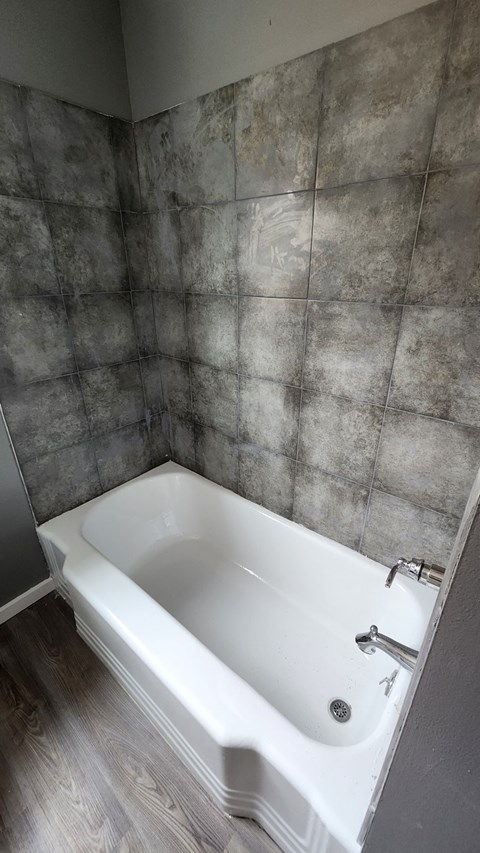 a white bath tub in a bathroom with grey walls