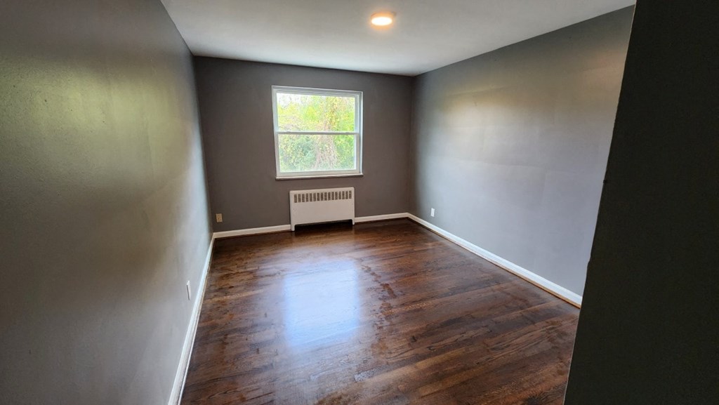 an empty room with wooden floors and a window