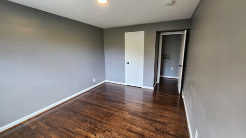 a empty living room with wooden floors and grey walls