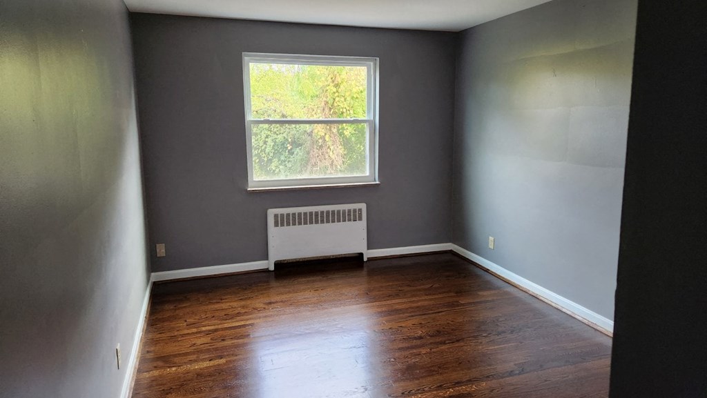an empty room with wooden floors and a window