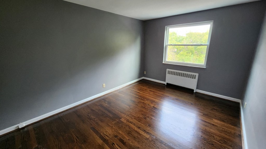 a bedroom with gray walls and a window and wooden floors