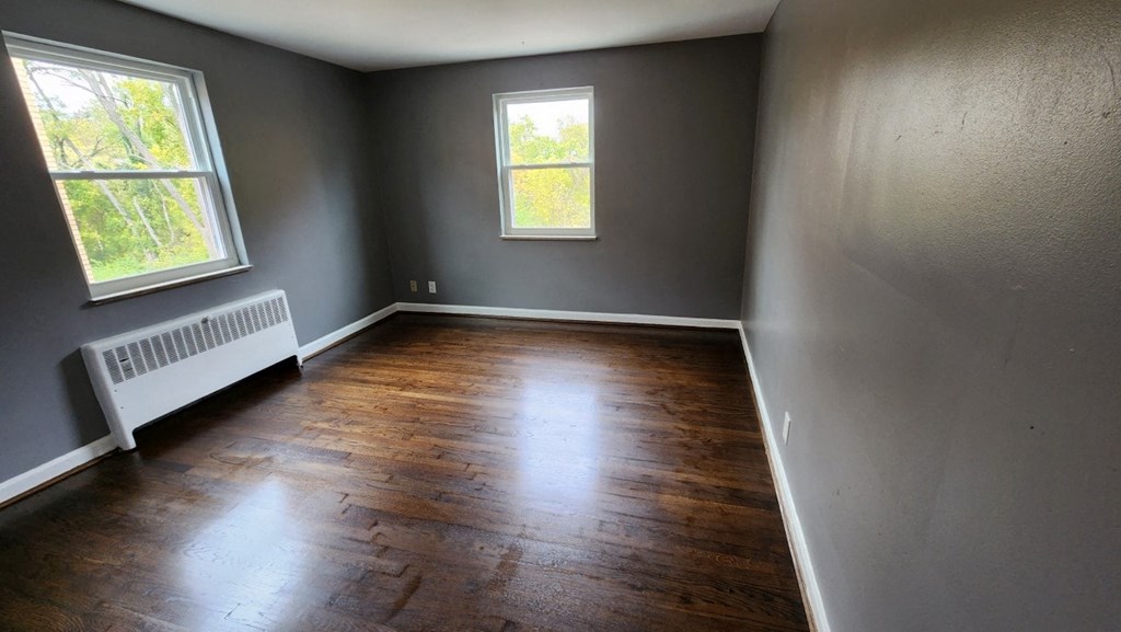 a empty room with wooden floors and grey walls and a window
